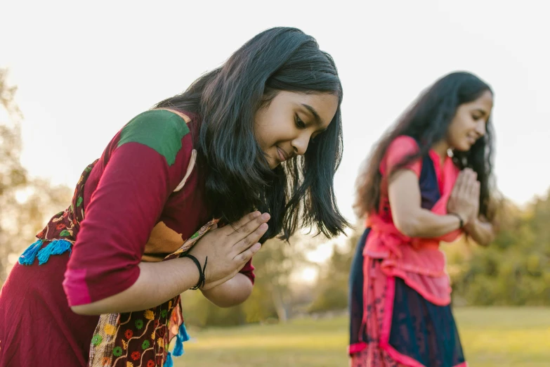 a couple of women standing on top of a lush green field, an album cover, pexels contest winner, hurufiyya, hindu stages of meditation, praying posture, red and blue garments, profile image