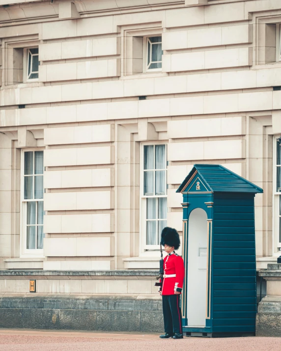 a man in a red uniform standing in front of a blue toilet, by Rachel Reckitt, pexels contest winner, on a great neoclassical square, queen victoria, telephone, military buildings