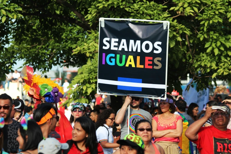 a group of people walking down a street holding signs, senor salme, lgbt, lumnoius colorful, thumbnail