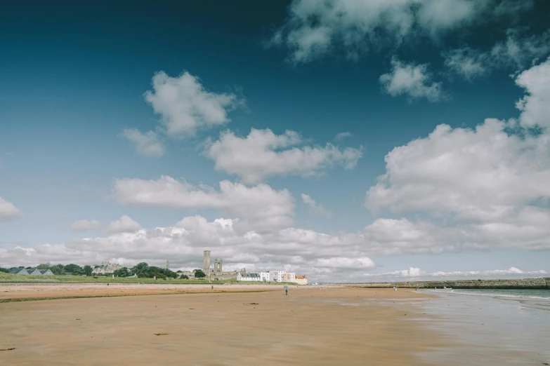 a man flying a kite on top of a sandy beach, unsplash, maryport, distant clouds, cityscape, large scale photo