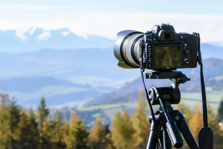 a camera on a tripod with mountains in the background, a picture, pexels contest winner, home video footage, holiday season, getty images proshot, panoramic photography