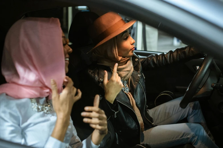 two women sitting in the driver's seat of a car, by Giuseppe Avanzi, pexels contest winner, hurufiyya, waving, wearing a head scarf, three women, square