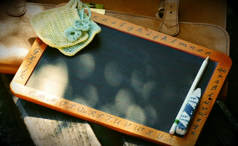 a chalk board sitting on top of a wooden table, letterboxing, shadow play, school girl, hand carved