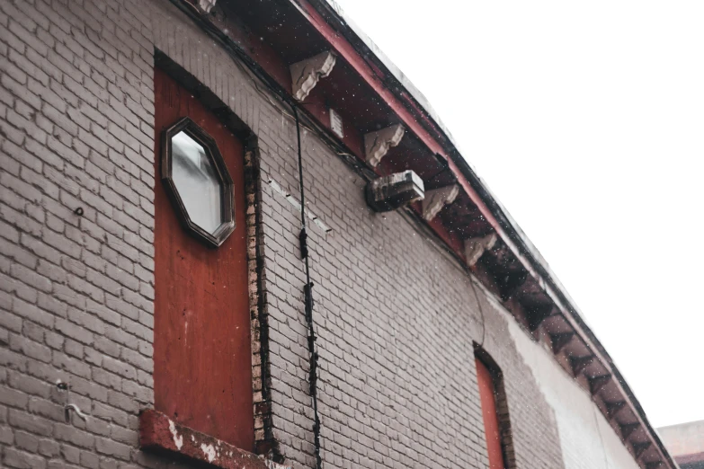 a red fire hydrant sitting in front of a brick building, inspired by Robert Bechtle, unsplash, snow outside the windows, wires hanging across windows, peaked wooden roofs, in a narrow chinese alley