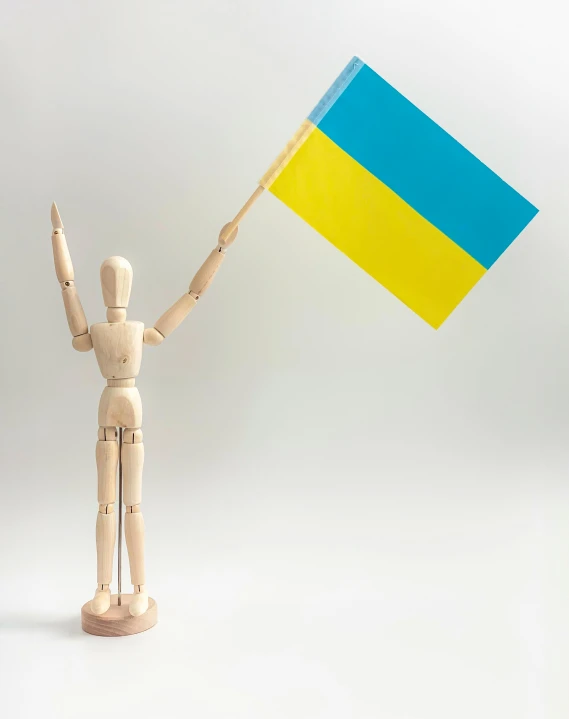 a wooden mannequin holding a ukraine flag, unsplash, triumphant pose, 2 colour print, single, 3 colour print