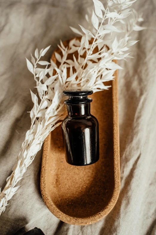 a small bottle sitting on top of a wooden tray, unsplash, renaissance, lush plant and magical details, black, thumbnail, linen