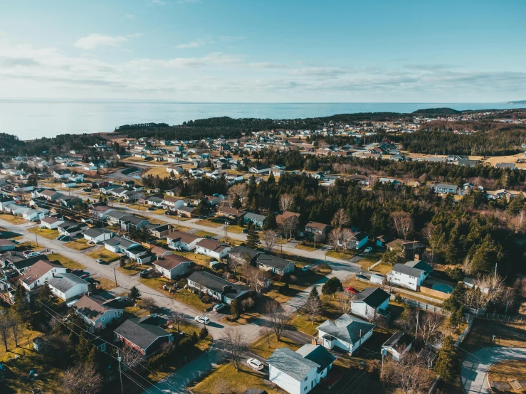 an aerial view of a small town with lots of houses, by Carey Morris, pexels contest winner, views to the ocean, emylie boivin, ultrawide angle cinematic view, viewed from bellow