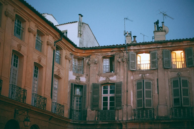 a couple of buildings that are next to each other, a photo, by Andrée Ruellan, pexels contest winner, neoclassicism, faded glow, shutters, early evening, view from side