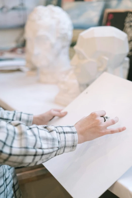 a person sitting at a table working on a piece of paper, a marble sculpture, trending on unsplash, low quality photo, on canvas, hands on face, ilustration