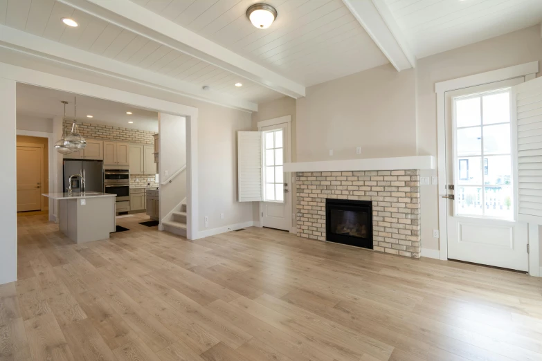 a living room with hardwood floors and a fireplace, by Carey Morris, unsplash, light and space, sand - colored walls, commercial, modeled, open ceiling