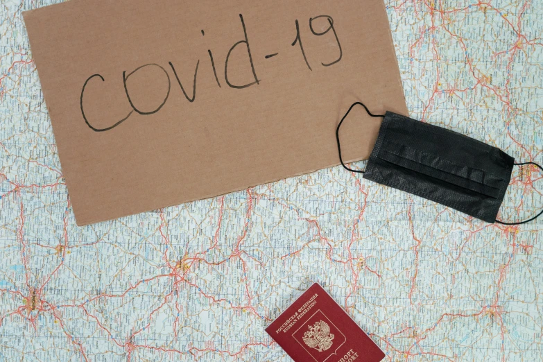 a brown sign sitting on top of a map next to a passport, pexels contest winner, graffiti, covid-19 as a human, package cover, dezeen, thumbnail