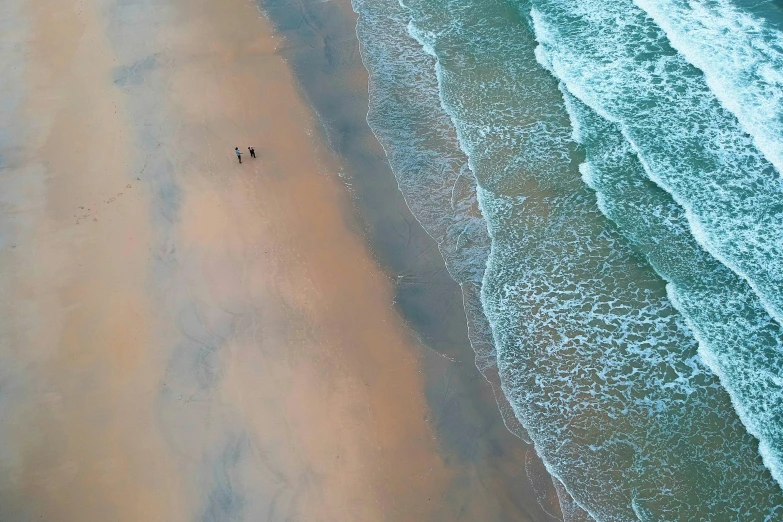 a couple of people standing on top of a sandy beach, inspired by Andreas Gursky, pexels contest winner, pristine rippling oceanic waves, bird's eye, walking to the right, cornwall