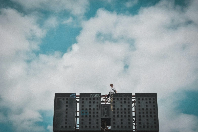 a man on a ladder on top of a building, by Adam Marczyński, pexels contest winner, brutalism, electronic billboards, sitting in a fluffy cloud, standing on top of a piano, billboard image