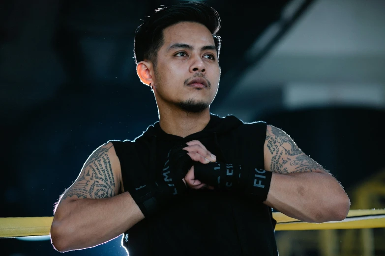 a man standing in the middle of a boxing ring, a tattoo, inspired by Eddie Mendoza, pexels contest winner, hurufiyya, tactical vests and holsters, avatar image, asian male, he is wearing a black t-shirt