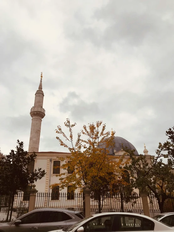 cars parked in front of a building with a clock tower in the background, a picture, by Ismail Acar, hurufiyya, with beautiful mosques, during autumn, ☁🌪🌙👩🏾, neo - classical style