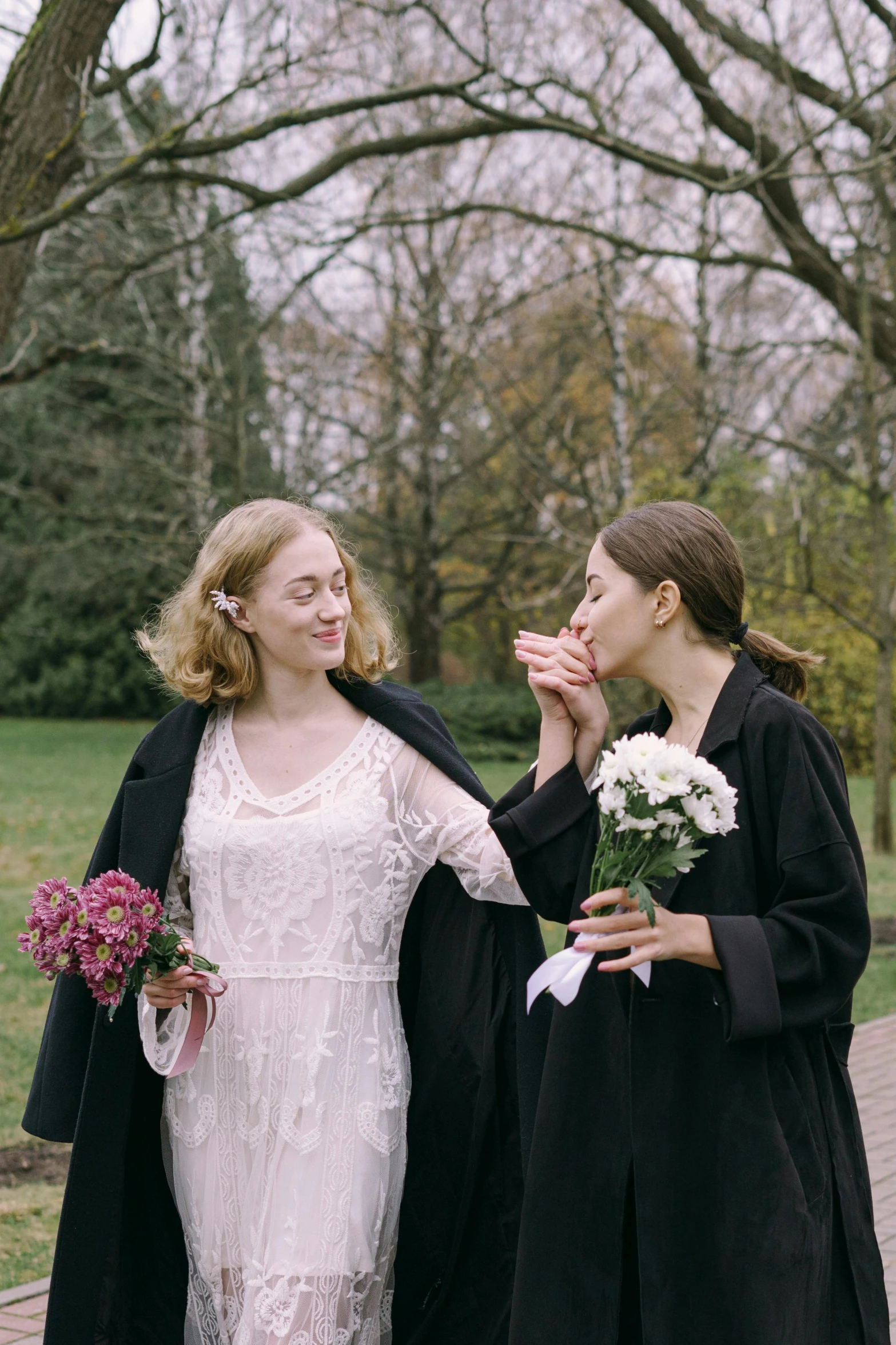 a couple of women standing next to each other, by Lucia Peka, unsplash, renaissance, holding a flower, wearing an academic gown, licking, film still promotional image