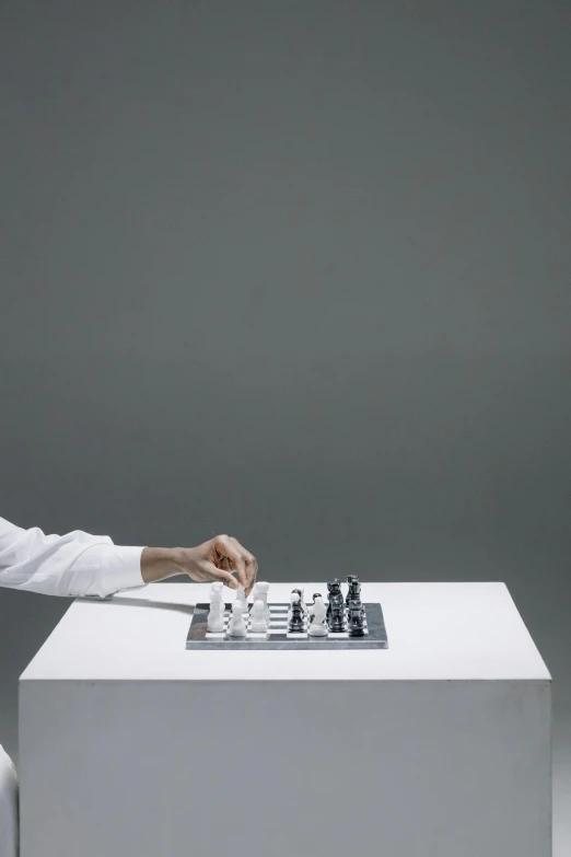 a man sitting at a table playing chess, inspired by Fei Danxu, interactive art, on grey background, white finish, tangible, ignant