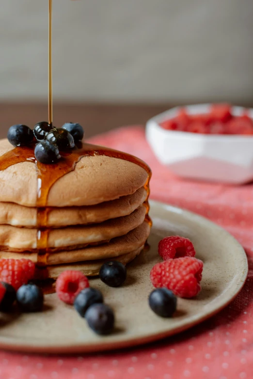 a stack of pancakes with syrup and berries on a plate, a still life, unsplash, hispanic, angled shot, oak, background image