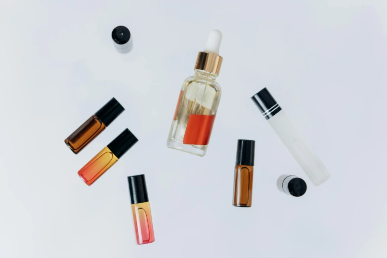 various bottles of perfume on a white surface, by Carey Morris, trending on pexels, red and orange glow, manuka, tubes, rectangle