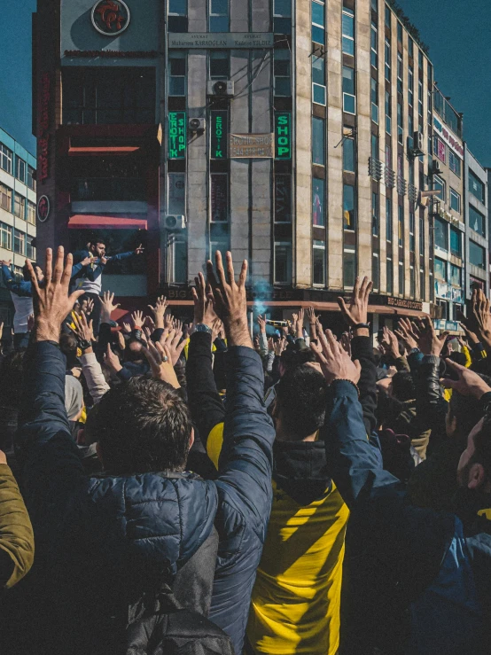 a crowd of people raising their hands in the air, by irakli nadar, pexels contest winner, happening, fallout style istanbul, yellow robes, 🚿🗝📝, square