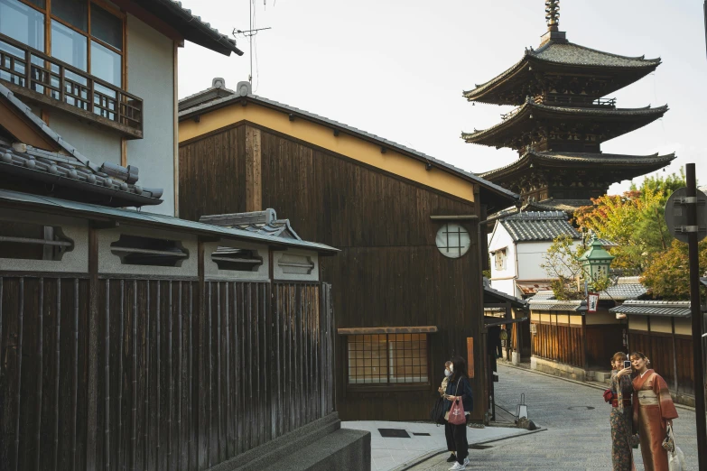 a couple of people that are standing in the street, inspired by Tōshi Yoshida, trending on unsplash, ukiyo-e, wooden structures, dry archways and spires, 2 0 0 0's photo, wooden houses