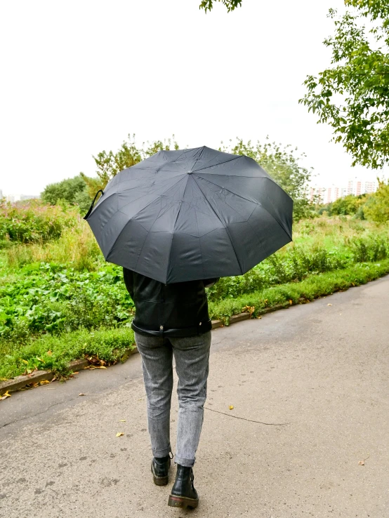 a person walking down a road with an umbrella, wearing a black jacket, walking at the garden, 155 cm tall, main colour - black