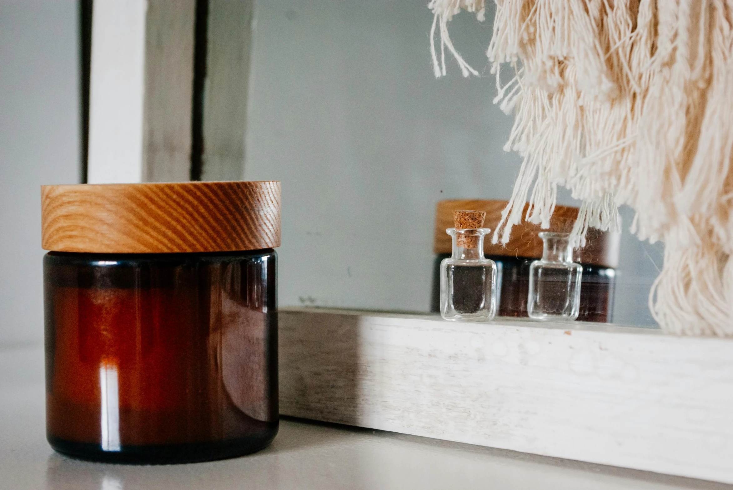 a brown jar sitting on top of a counter next to a mirror, pexels contest winner, glass vials, manuka, wood accents, gif