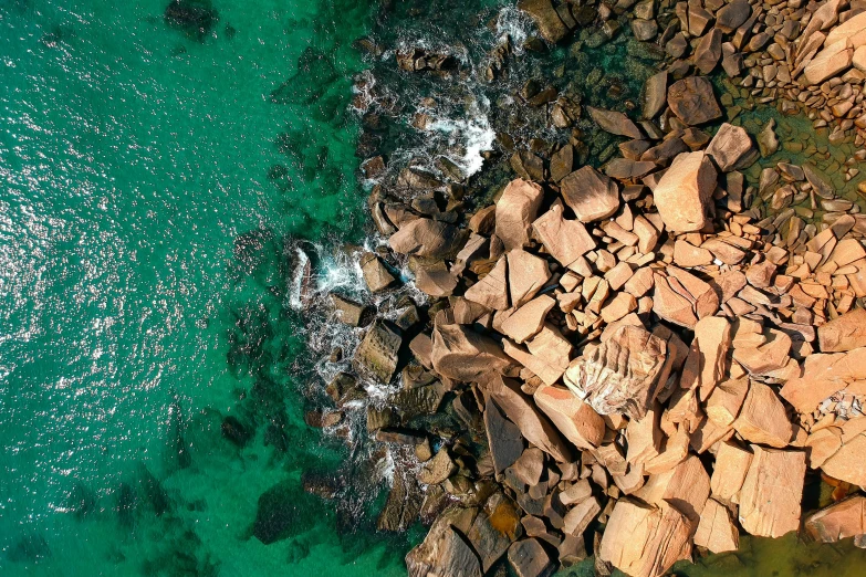 a group of rocks sitting on top of a body of water, by Peter Churcher, pexels contest winner, copper and emerald, aerial photo, manly, conde nast traveler photo