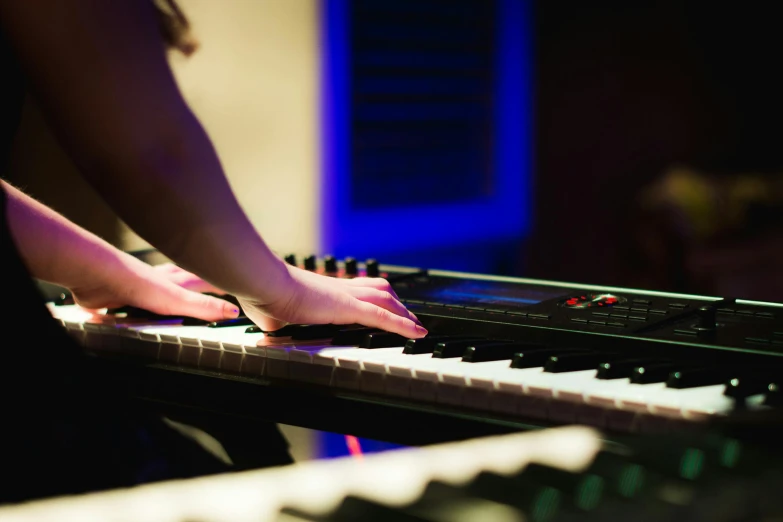 a close up of a person playing a keyboard, 5 feet away, during the night