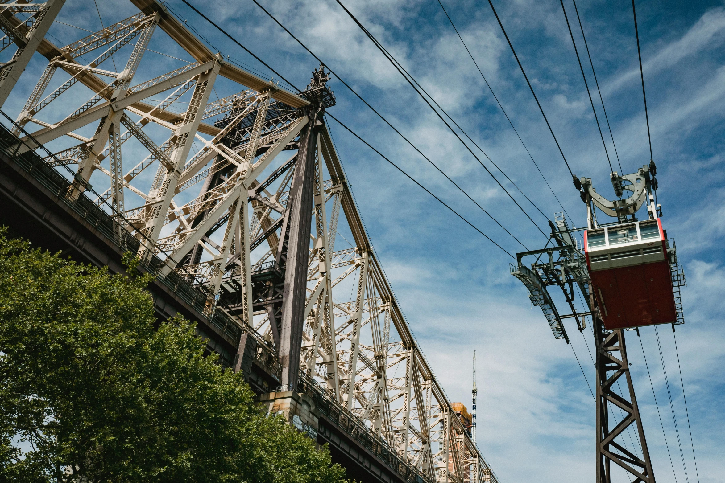 a view of a train going over a bridge, a portrait, unsplash contest winner, streets of new york, telephone wires, mechanical superstructure, summer day