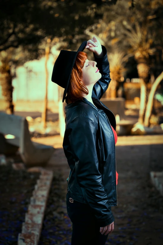 a woman standing in the middle of a cemetery, an album cover, unsplash, realism, triss merigold cosplay, black leather jacket, black hat, ((portrait))