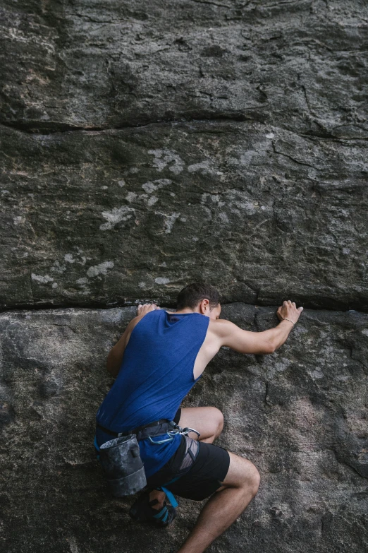 a man climbing up the side of a rock, by Andrew Domachowski, pexels contest winner, renaissance, very sweaty, back arched, hands, blue