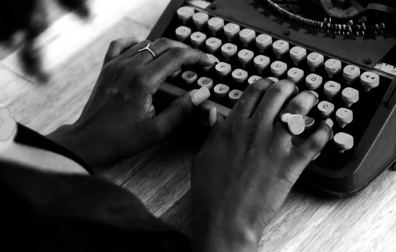 a person typing on an old fashioned typewriter, a black and white photo, by Emma Andijewska, unsplash, ebony skin, black jewellery, mulato, coding