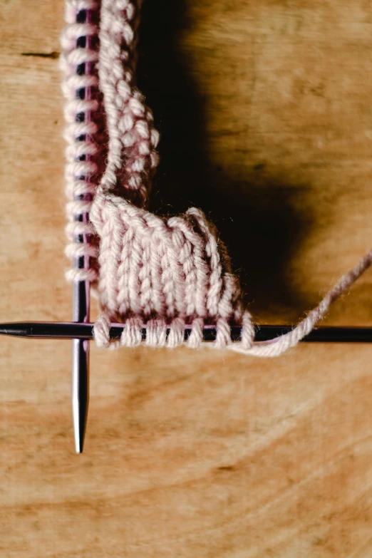 a close up of a knitting needle on a wooden surface, unsplash, centered design, bending down slightly, half image, fighting