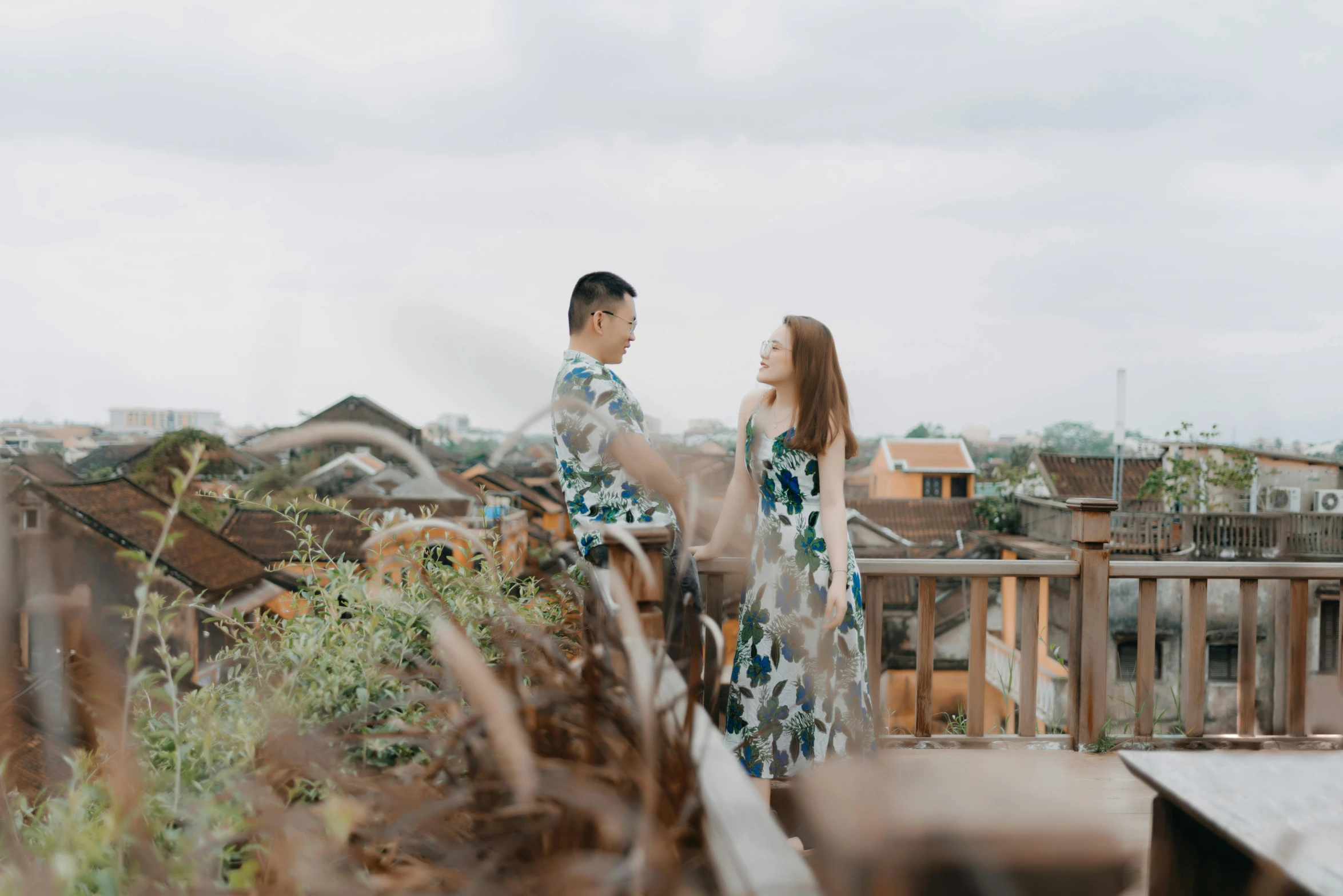 a man and woman standing on top of a roof, a portrait, inspired by Ruth Jên, pexels contest winner, ao dai, background image, low quality footage, nature photo