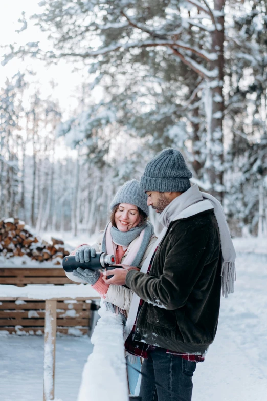 a man and woman standing next to each other in the snow, pexels contest winner, forest picnic, hot cocoa drink, inspect in inventory image, wood