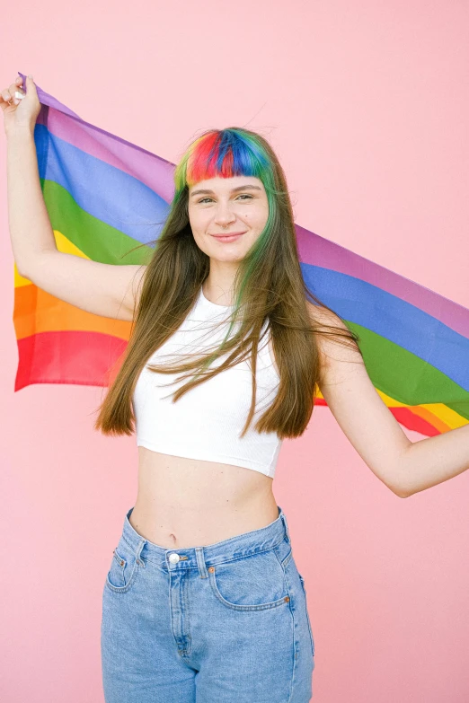 a young woman holding a rainbow flag against a pink background, by Julia Pishtar, trending on pexels, brown colored long hair, e - girl, 🚿🗝📝