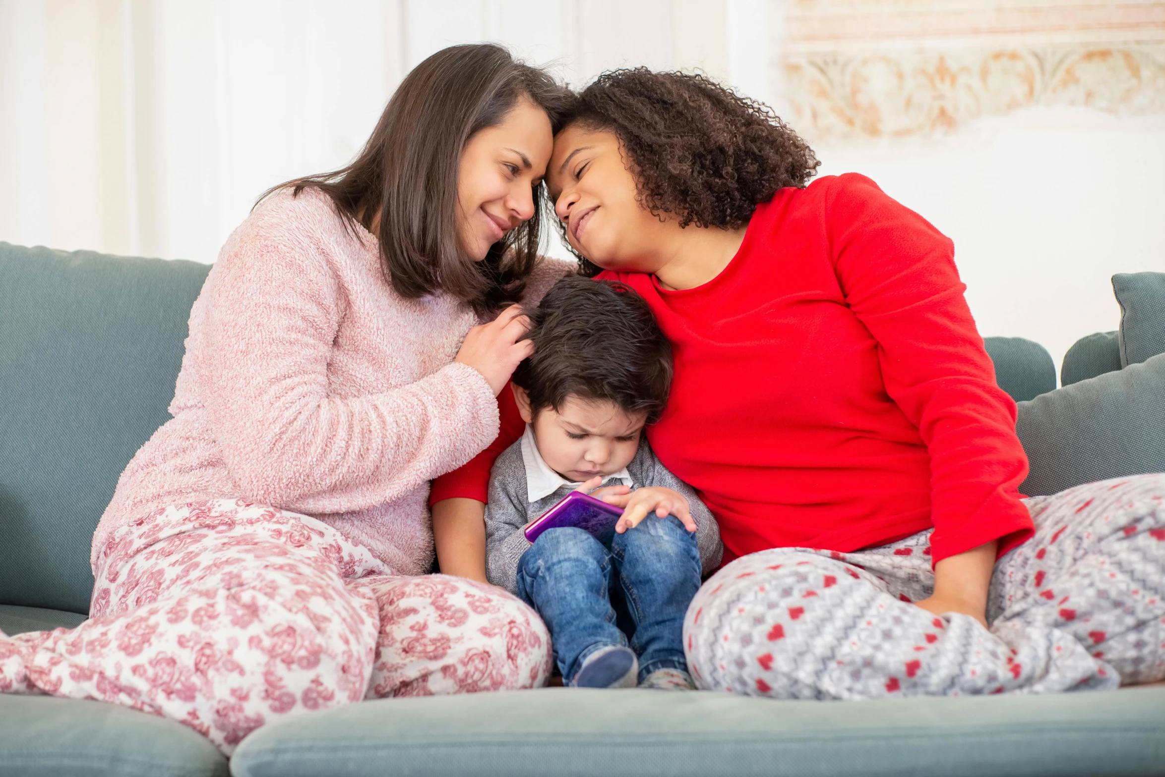 two women and a child sitting on a couch, by Lisa Milroy, pexels, red sweater and gray pants, avatar image, wearing pajamas, spanish