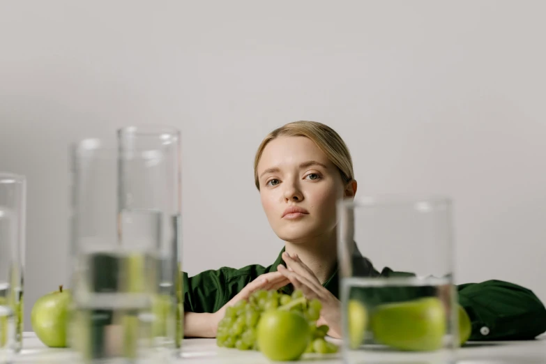 a woman sitting at a table with a bunch of grapes, unsplash, hyperrealism, stood in a lab, human staring blankly ahead, greens), transhumanist hydration