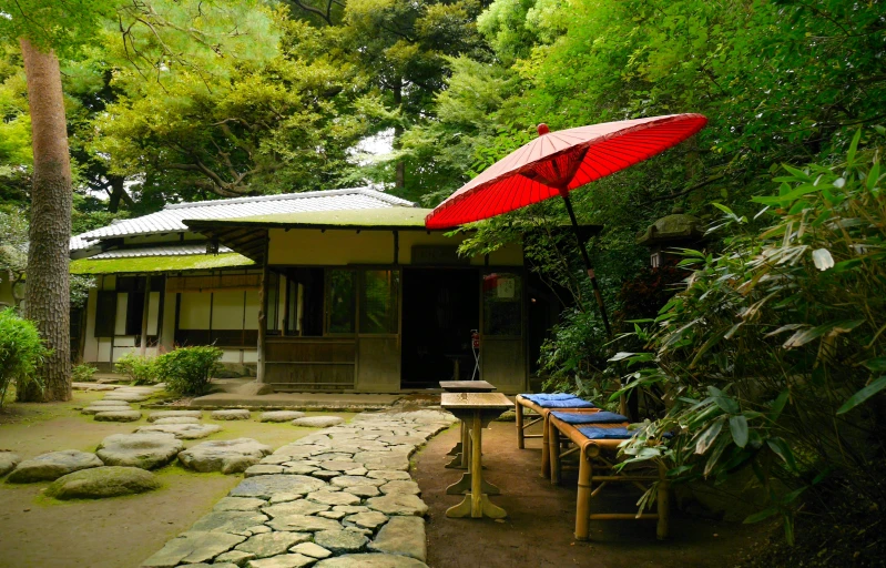 a red umbrella sitting on top of a wooden table, shin hanga, lush garden surroundings, exterior shot