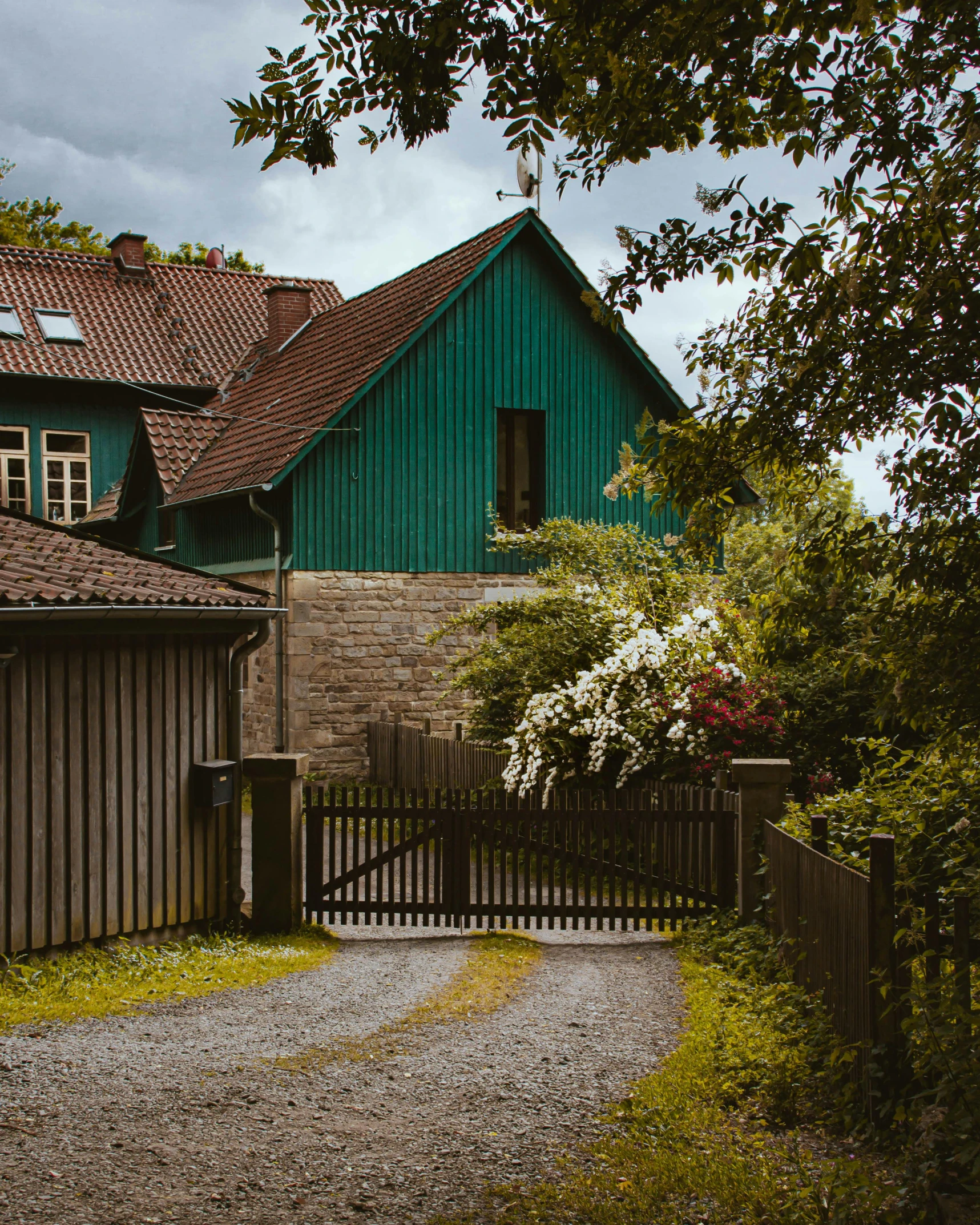 a green house with a driveway leading to it, by Sebastian Spreng, pexels contest winner, arts and crafts movement, hammershøi, large gate, earthy color scheme, modern house made of tree