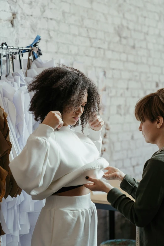 a woman standing next to a boy in a room, trending on pexels, renaissance, touching her clothes, with afro, wearing a white sweater, customers