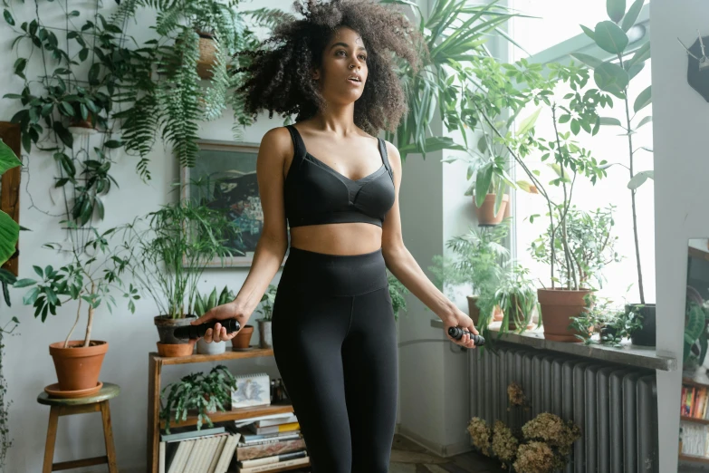 a woman in a black bra top and black leggings, inspired by Esaias Boursse, biophilia mood, in background, lifestyle, ebony