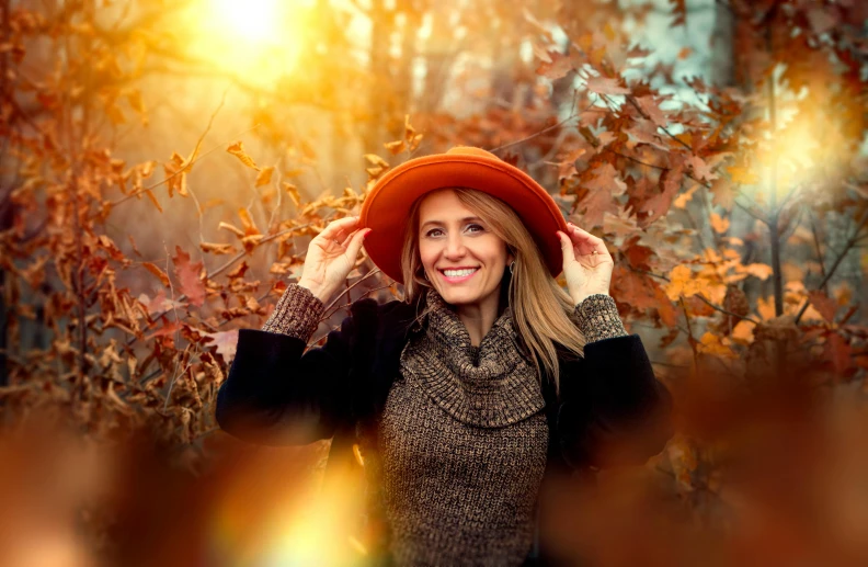 a woman in a hat is posing for a picture, a photo, by Zofia Stryjenska, pexels contest winner, autumn lights colors, warm smile, orange halo, youtube thumbnail