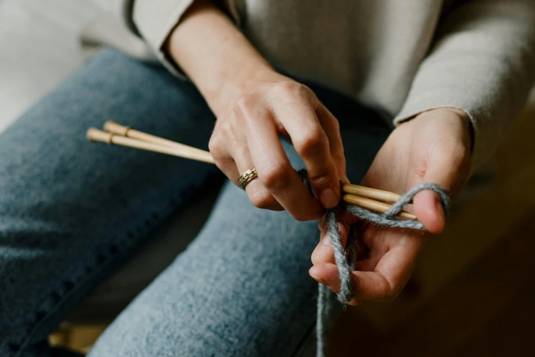 a close up of a person holding a pair of knitting needles, inspired by Sarah Lucas, trending on pexels, double denim, grey, cottagecore, webbing