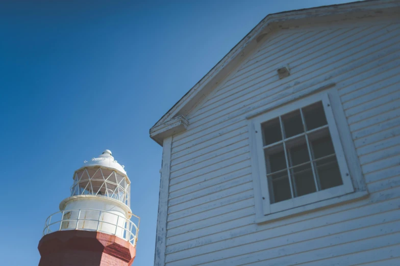 a red and white lighthouse next to a white house, unsplash, light and space, picton blue, medium format. soft light, fresnel effect, profile image