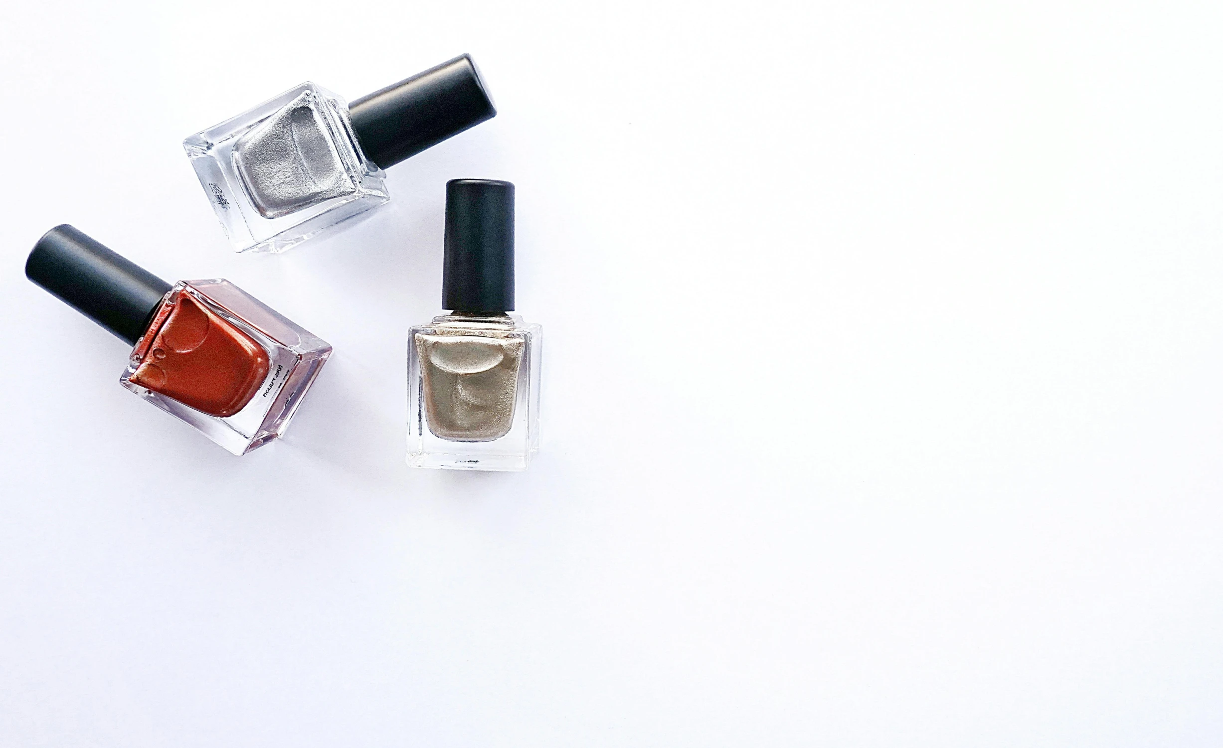three bottles of nail polish on a white surface, by Gavin Hamilton, pexels, gradient brown to silver, square, background image, fashionable