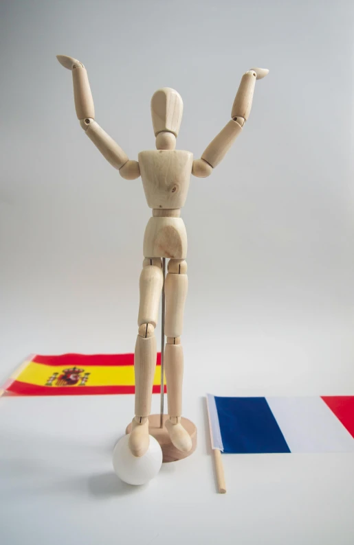 a wooden mannequin standing in front of a flag, inspired by Francisco de Holanda, pose(arms up + happy), tournament, david a, in spain