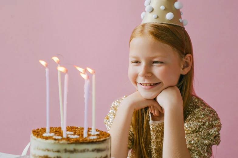 a little girl sitting in front of a birthday cake, an album cover, pexels, background image, wearing crown, candle lighting, young teen