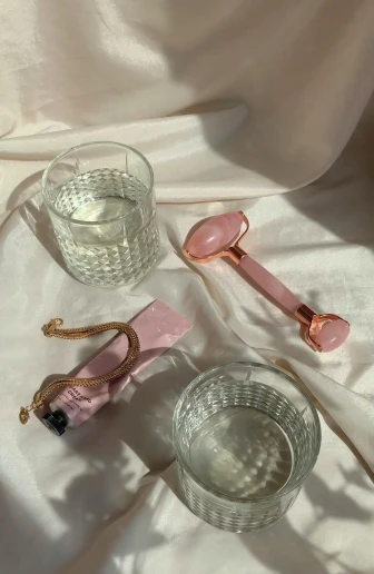 a couple of glasses sitting on top of a table, light pink, various items, with shiny skin, detail shot